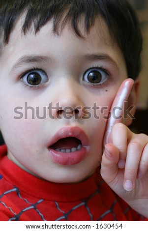 A very expressive boy carried away in telling his story to his audience with cream melting on his index finger