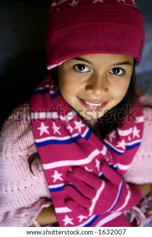 A pretty young girl wrapped up for winter in her hat, scarf , glove and poncho