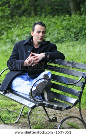 A young man enjoying the outdoors, relaxing on a park bench