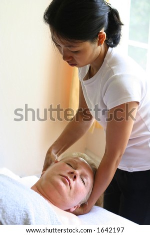 A masseur treating her client with holistic head massage