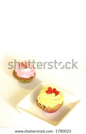 Two mini cupcakes on white plates, isolated on white