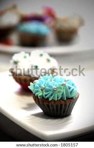 Plates of mini cupcakes with butter frosting and silver ball sprinkle
