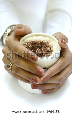 Time out and unwind. A pair of feminine hands around a cup of hot cappuccino coffee.