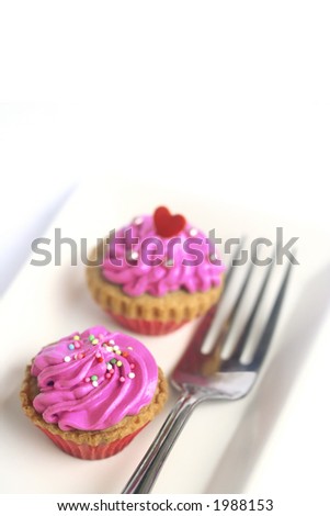 Two mini cupcakes on white plate, on white background with copyspace.