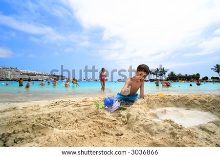 A brother and sister helping each other at making sand castle by the beach on tropical island holiday.