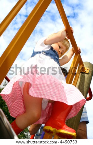 Girl toddler about to go down the slide in the playground.