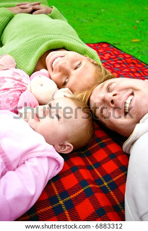 Young family with baby daughter enjoying the outdoor, relaxing in the park