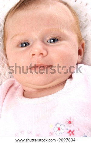 Newborn baby girl smiling back at photographer.