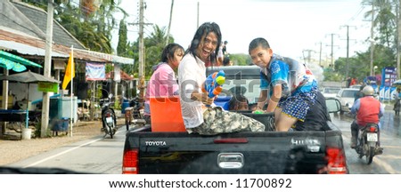 Young Thai man shooting water towards photographer with super soaker from back of pickup truck as the nation celebrates the Thai Songkran Water festival to mark the start of the Thai new year