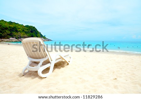 A sun lounger by a sandy beach against crystal blue sea and blue sky of Phuket beach, Thailand