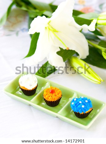 Three mini cupcakes with sugar frosting on green plate