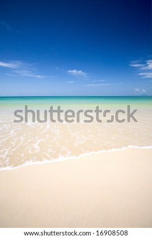 Crystal clear waters of the Andaman sea with soft white sand and clear blue sky.