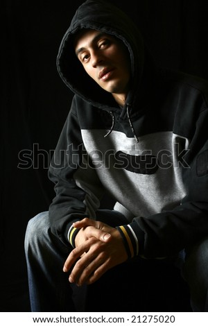 Young man in hooded top in low key.