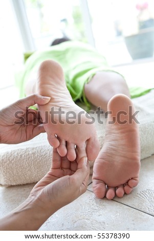 Woman receiving foot reflexology by therapist