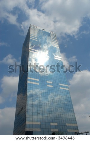 office building, skyscraper against dramatic blue cloudy sky. Circle on top is window, not logo.