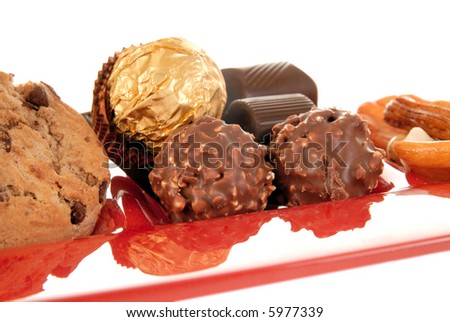 Belgium chocolates truffles, brownies and mix of cookies and nuts on a decorative red glass  plate. Copy space provided