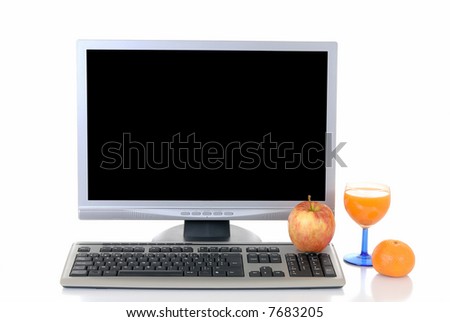 Computer screen and keyboard with apple, mandarin and glass of fruit juice  in front on reflective surface.  White background