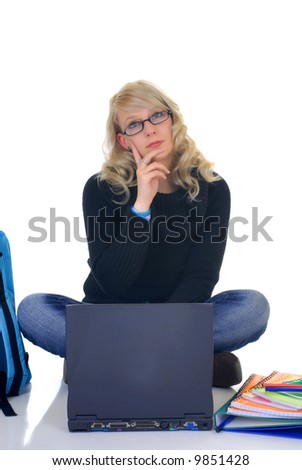 Attractive trendy blond teenager student doing schoolwork on laptop, books and backpack on the side,  white background,