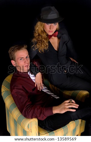 Attractive young classy couple, formal clothing, woman wearing suit and bow tie.  Studio shot, black background.