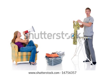 Young bossy woman shouting with megaphone to husband ironing clothing. Studio, white background.