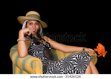 Attractive young classy retro style woman, lady sitting in arm chair holding flower.  Studio shot, black background.