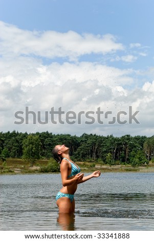 Young woman in bikini swimming in meadow lake.