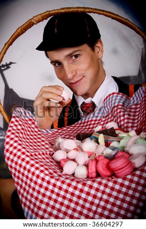 Young Halloween male with English boarding school student outfit gulping sweets.    Studio shot, painted background.