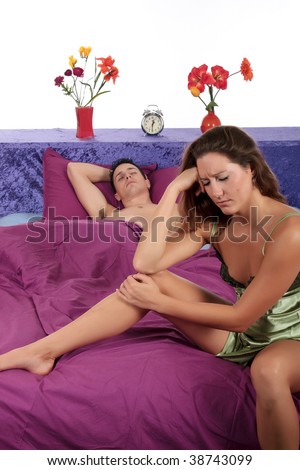 young  couple on bed in bedroom, woman having a depression moment while husband sleeping.  Studio.