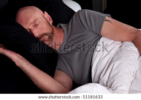 Bald Middle aged man sleeping, first light of morning appearing in bedroom.