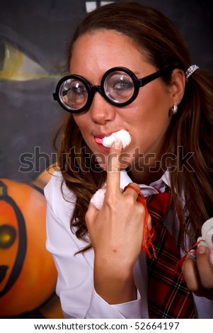 Young Halloween female with English boarding school student outfit gulping sweets.    Studio shot, painted background.