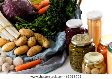 Basket with fresh vegetables versus canned vegetables in jars. Studio shot. White background. Copy space.