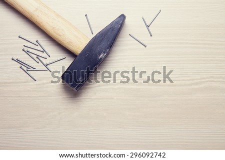 Construction tools lying on a wooden surface. The hammer and nails top view. Color effects