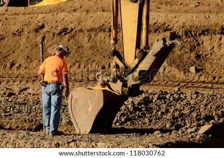 Excavator track hoe digging foundation trenches at a new commercial housing development