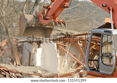A track hoe excavator using its claw thumb to tear down an old hotel to make way for a new commercial development