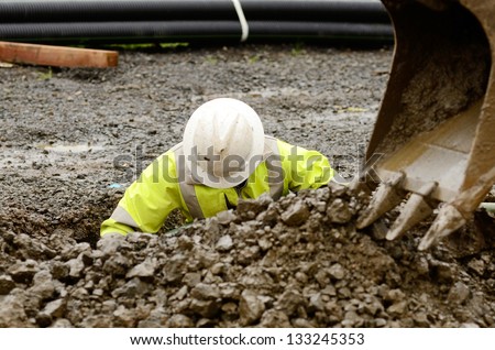 Worker using a small tracked excavator to dig a hole to fix a water leak at a large commercial housing development in Oregon