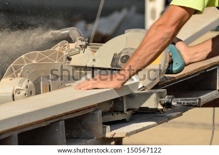 Carpenter uses a compound electric cut off saw to cut trim boards for a new commercial residential project