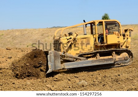 Large bulldozer moving rock and soil for a fill lift at a new commercial development road construction project
