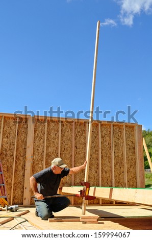 Building contractor worker using a wall jack to raise a wall for the second floor on a new home constructiion project
