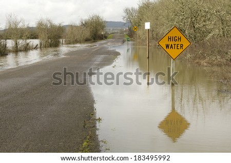 A high water sign sits in a few feet of water on a flooded road in rural west Oregon following a heavy rain storm