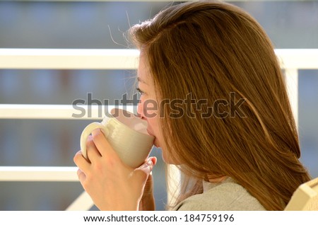 Krystal Fox A young female adult drinks her morning tea on a balcony of a condo
