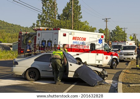ROSEBURG, OR, USA - MAY 30, 2014: Police and fire fighters survey the scene of a single vehicle accident due to excessive speed sends the driver to the hospital in Roseburg, OR, on May 30, 2014