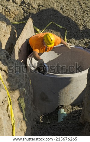Excavation contractor installing a riser on a manhole vault on a sanitary sewer system on a new commercial development