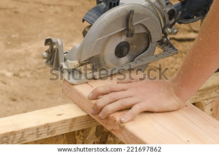 Framing contractor using a circular hand  saw to trim wood studs to length.