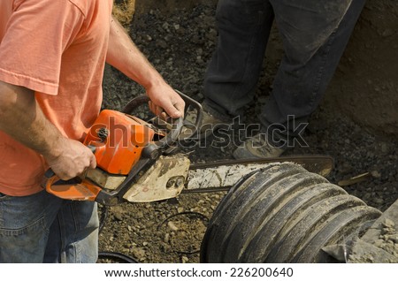 Excavation contractor uses a chain saw to cut plastic drain pipe for a new commercial street storm drain sewer