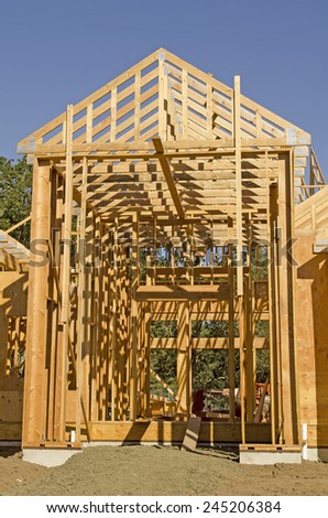A single family home under construction. The house has been framed and covered in plywood and roof trusses in place.