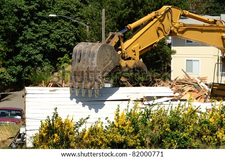A large track hoe excavator tearing down an old hotel to make way for a new commercial development