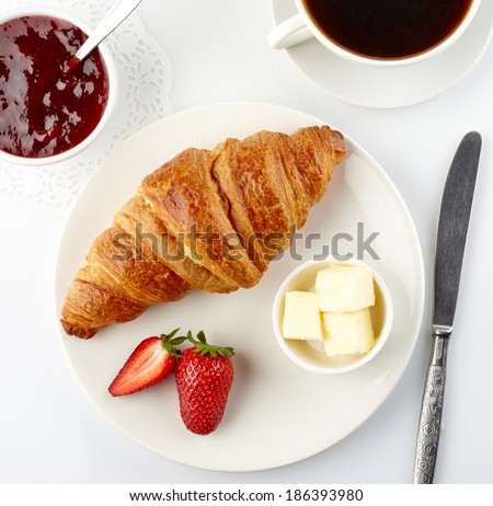 Plate of fresh croissant and cup of coffee on white background