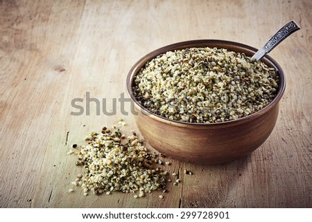 Bowl of shelled hemp seeds on wooden background