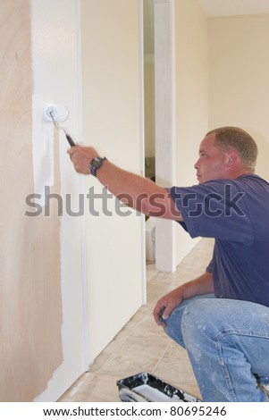 Painter painting dining room wall with roller brush