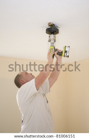 Electrician installing new light fixture and fan